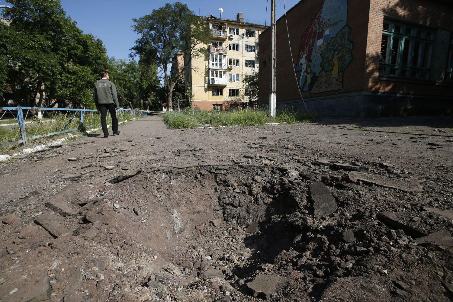 Gránát szakította krátert kerül meg egy kelet-ukrajnai lakos