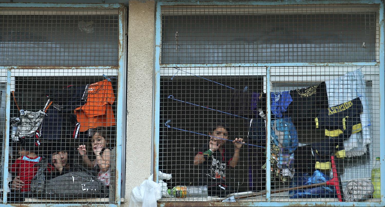 Palesztin gyerekek figyelik a mozgást a lebombázott gázai ENSZ-iskolánál