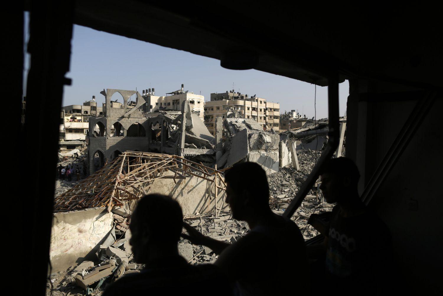 Egy gázai mecsset romjait nézik rakétatalálat után palesztin civilek