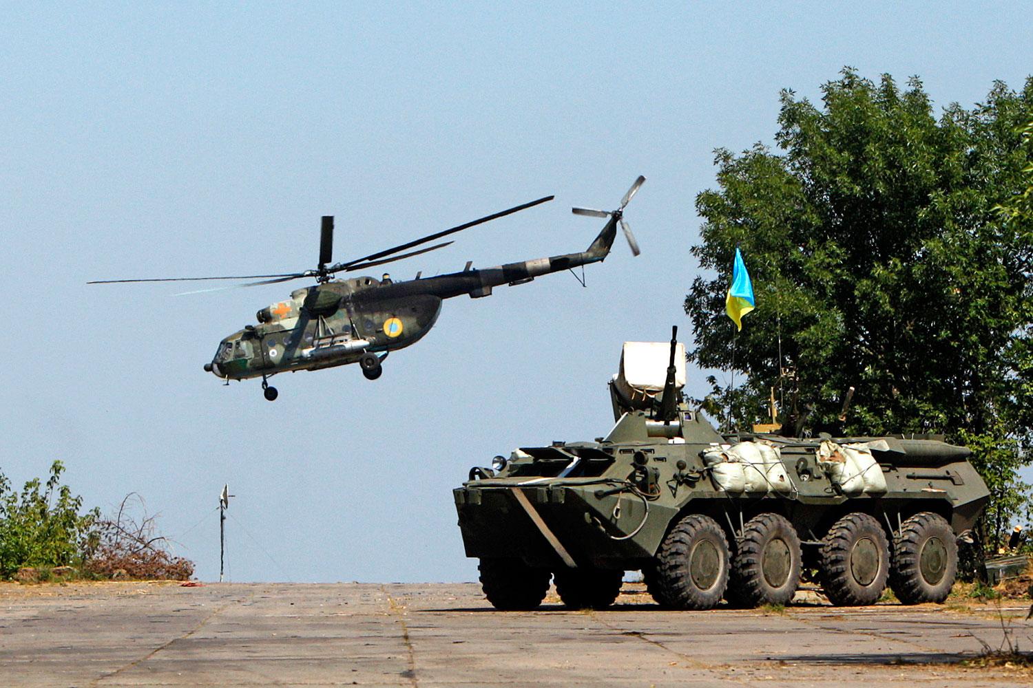 Ukrán helikopter repül egy páncélozott szállító harcjármű mellett Donyeckben