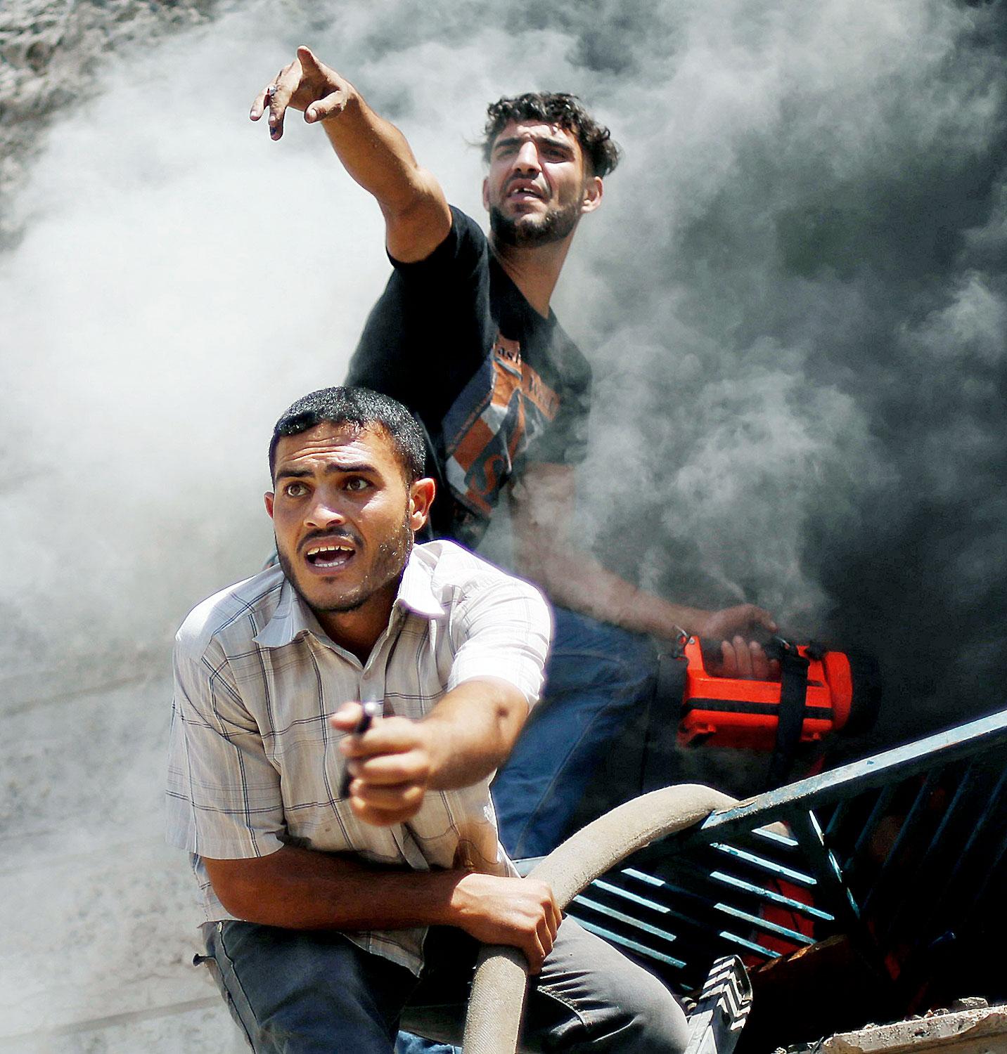 Palesztin férfiak tüzet oltanak egy izraeli légicsapás után a Gázai övezetben