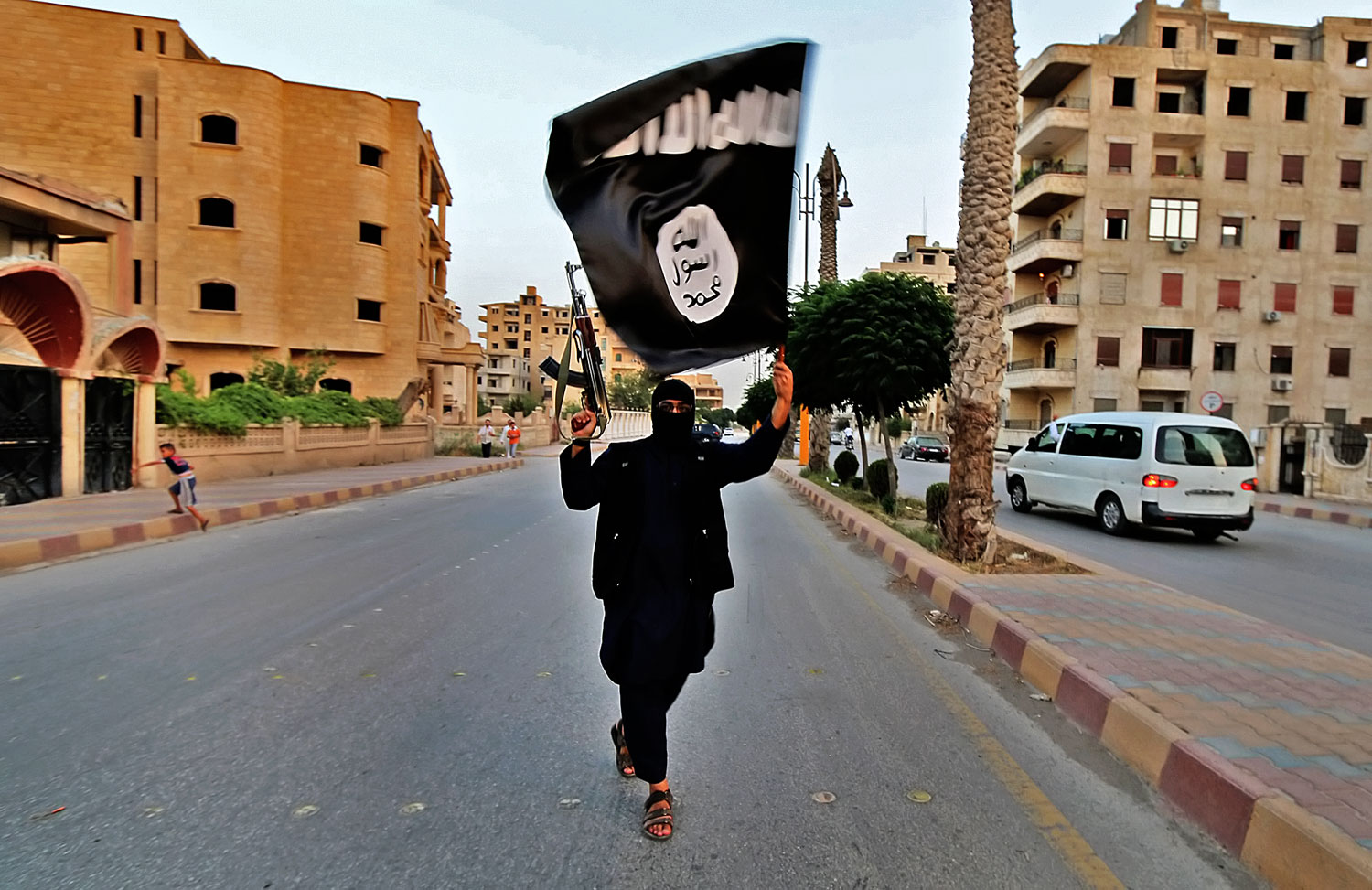 Az IS zászlóját lengeti egy harcos a szíriai Rakka utcáján