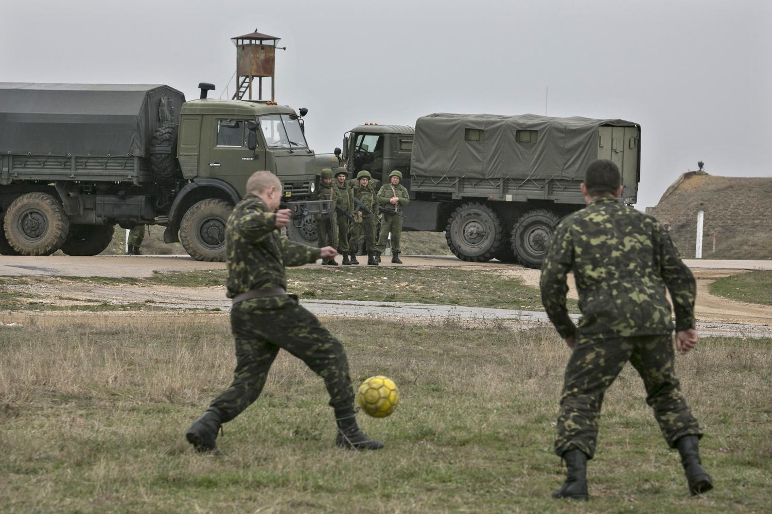 Orosz katonák figyelik, ahogy krími ukránok fociznak 2014 márciusában