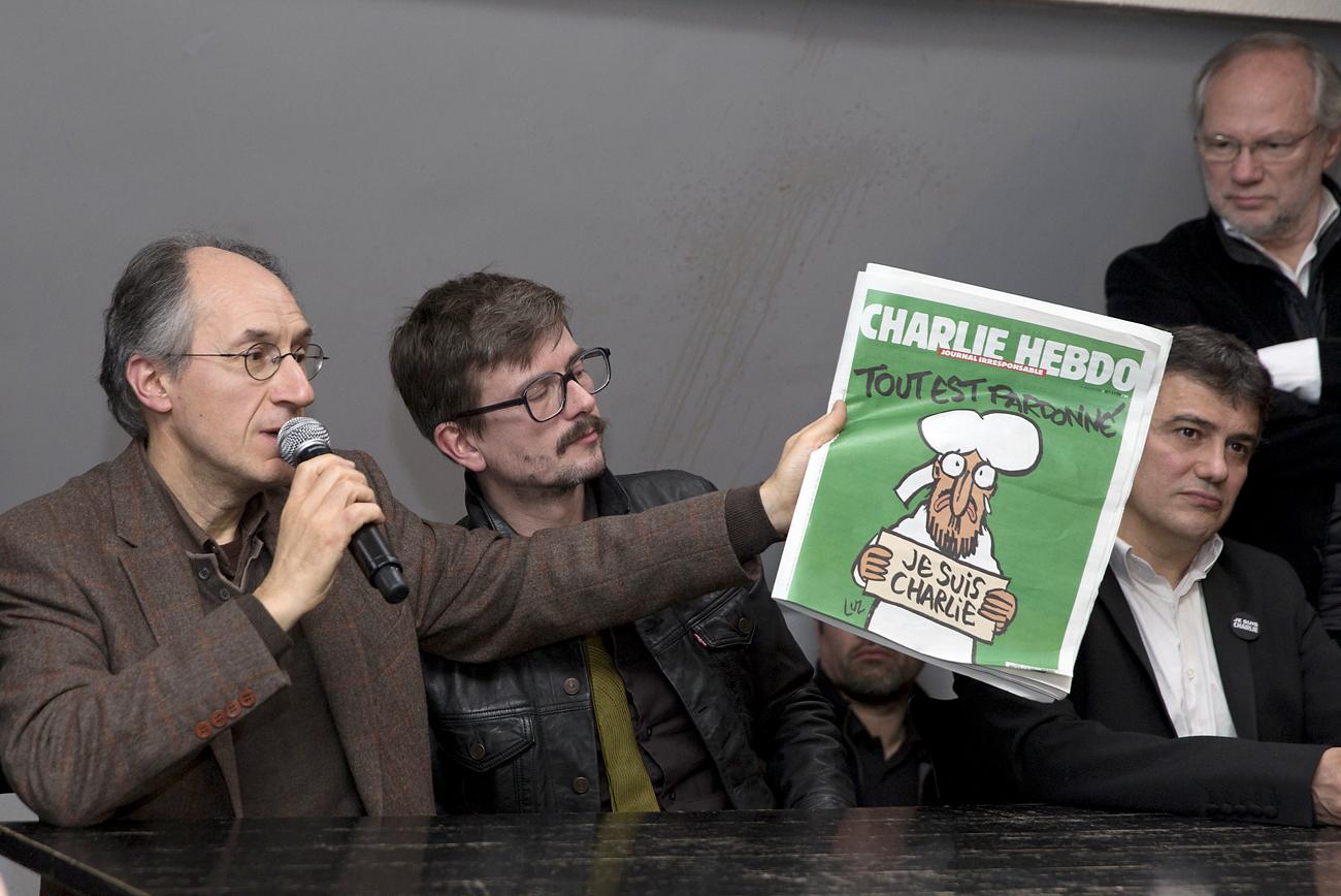Gerard Briard (B) új főszerkesztő mutatja be a Charlie Hebdo legújabb számának címlapját, melynek szalagcíme: Minden meg van bocsátva!