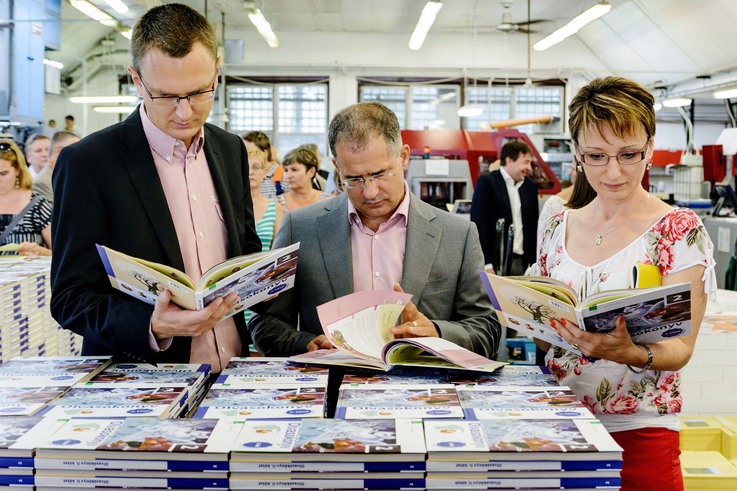 Rétvári Bence államtitkár, Kósa Lajos fideszes politikus és Czunyiné Bertalan Judit szemlélik az új tankönyveket a nyomdában