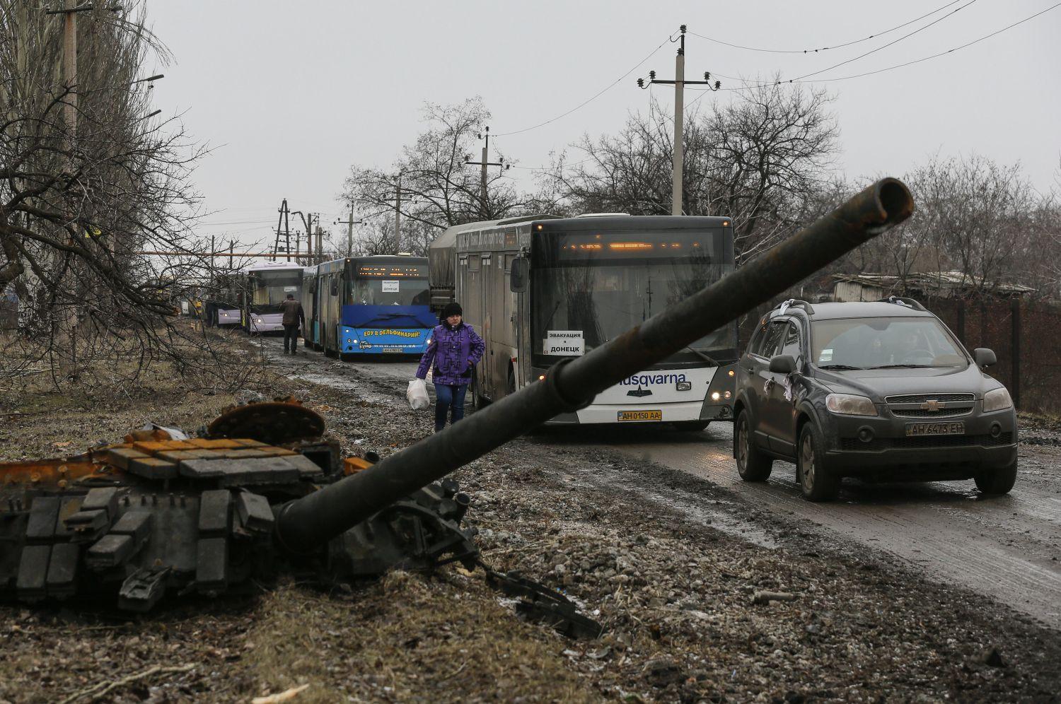 Menekülteket szállító buszok haladnak egy egy kilőtt tank mellett a stratégiai jelentőségű város, Vuhlehirszk mellett