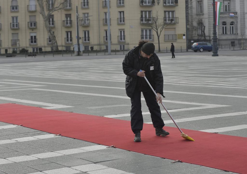 Egy munkás söpri a vörös szőnyeget Budapesten, a Hősök terén Vlagyimir Putyin orosz elnök érkezése előtt