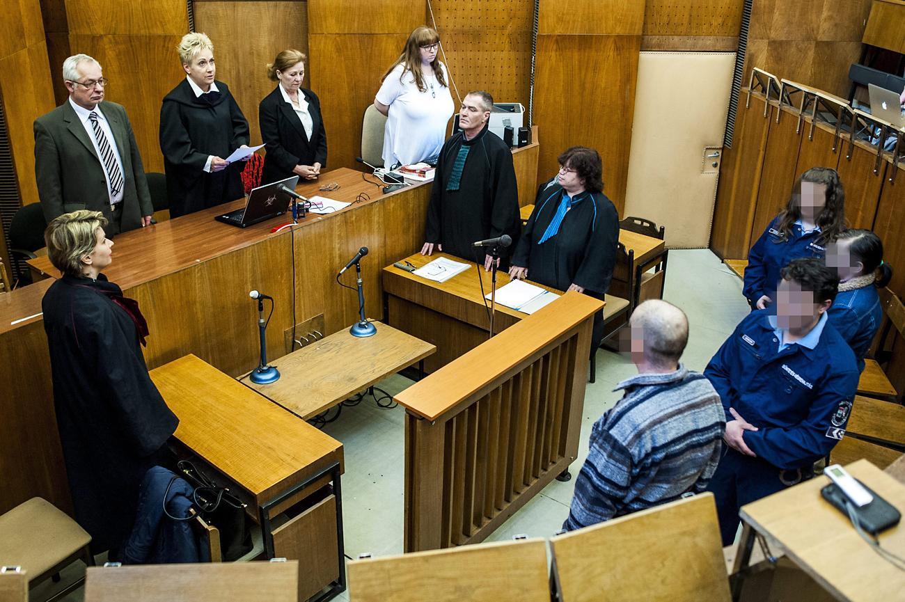 Szegedi Gyöngyvér bírónő (balról a harmadik) felolvassa az ítéletet K. Rudolf és felesége büntetőperén. Egymásra mutogatnak az ügyészséggel