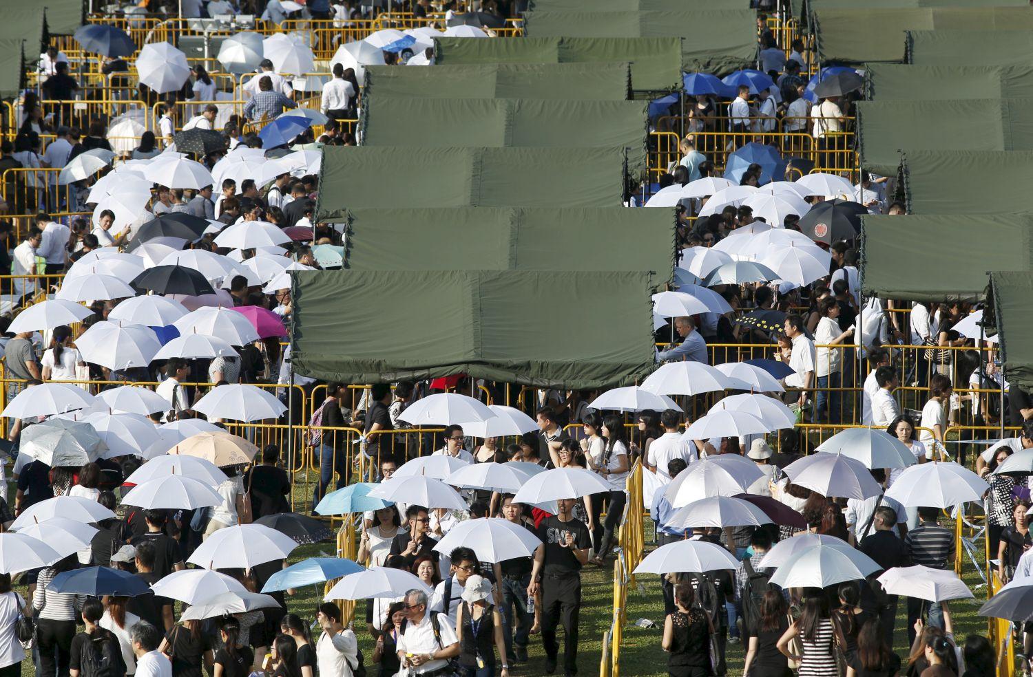 Esernyővel védik magukat a nap ellen a szingapúriak, miközben arra várnak, hogy a ravatal közelébe kerülhesennek