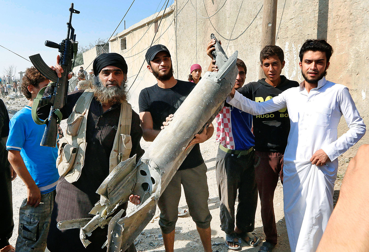 Az Iszlám Állam harcosa (balra) a szíriai Raqqa lakóival egy lezuhant szír vadászgép darabját tartja