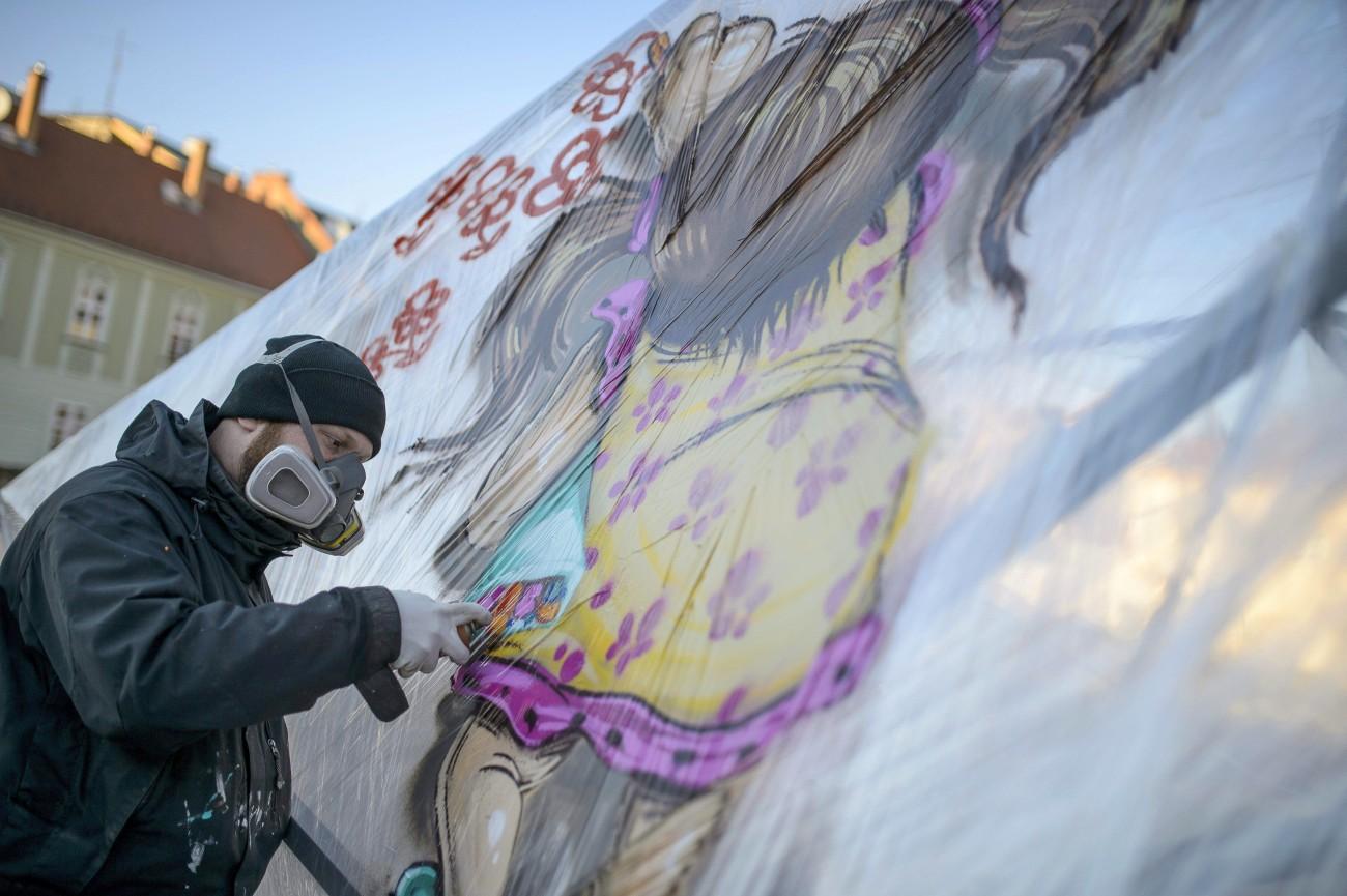 A Mr. Zero művésznevű graffitiművész festékszóróval fest az egri Gárdonyi téren