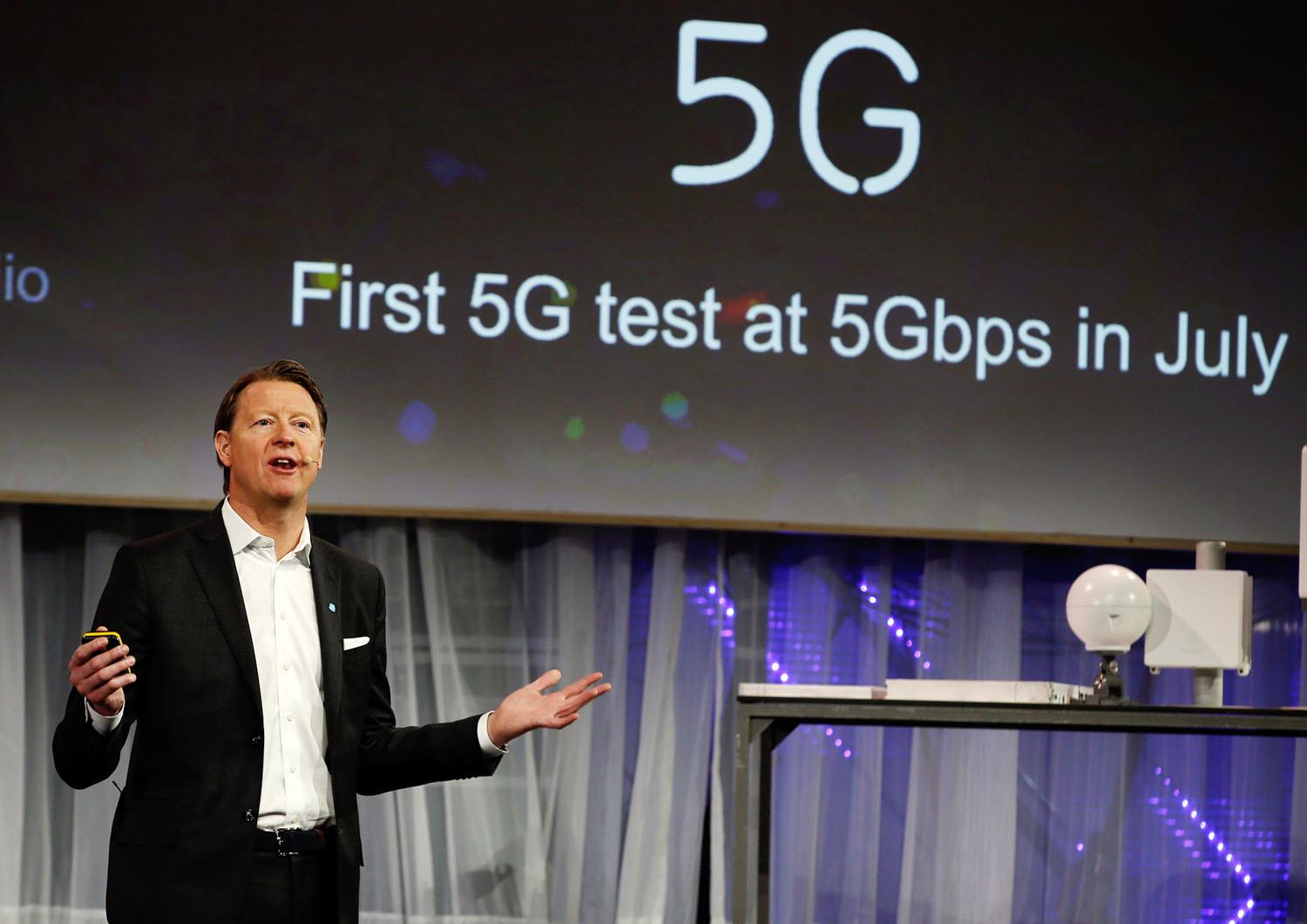 Hans Vestberg, az Ericsson főnöke az 5G-ről beszél, a jobb oldali képen a Huawei okosórája látható
