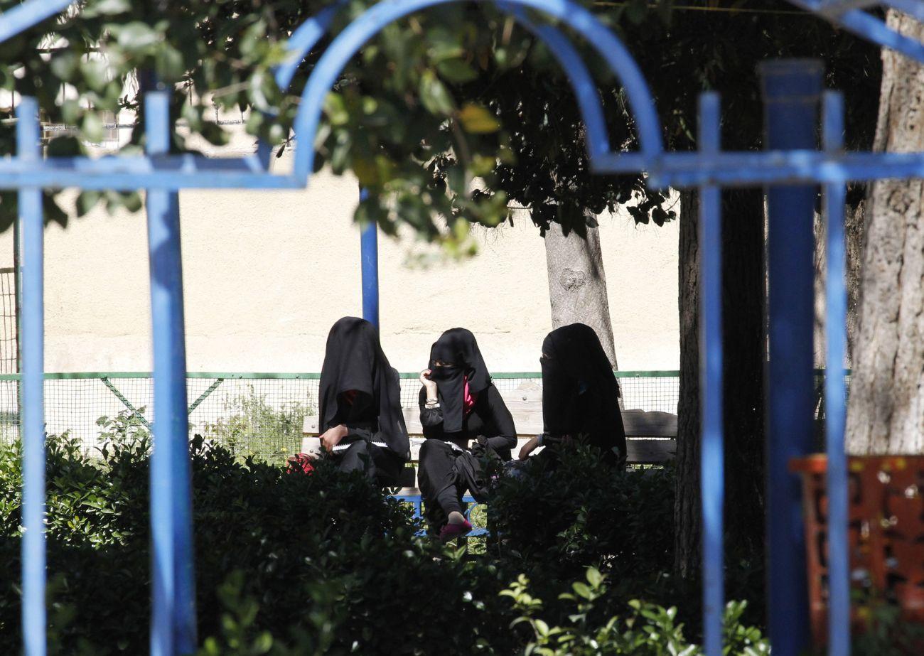 Földig érő fekete köntös, abaját és az arcot a szemen kívül eltakaró fátylat, nikábot viselő nők az Iszkám Állam de facto fővárosában, a szíriai Rakkában