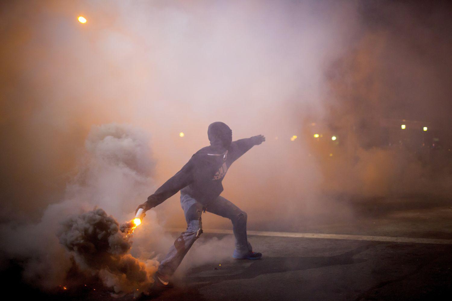Az egyik tüntető füstgránátot dob vissza a rendőrök közé