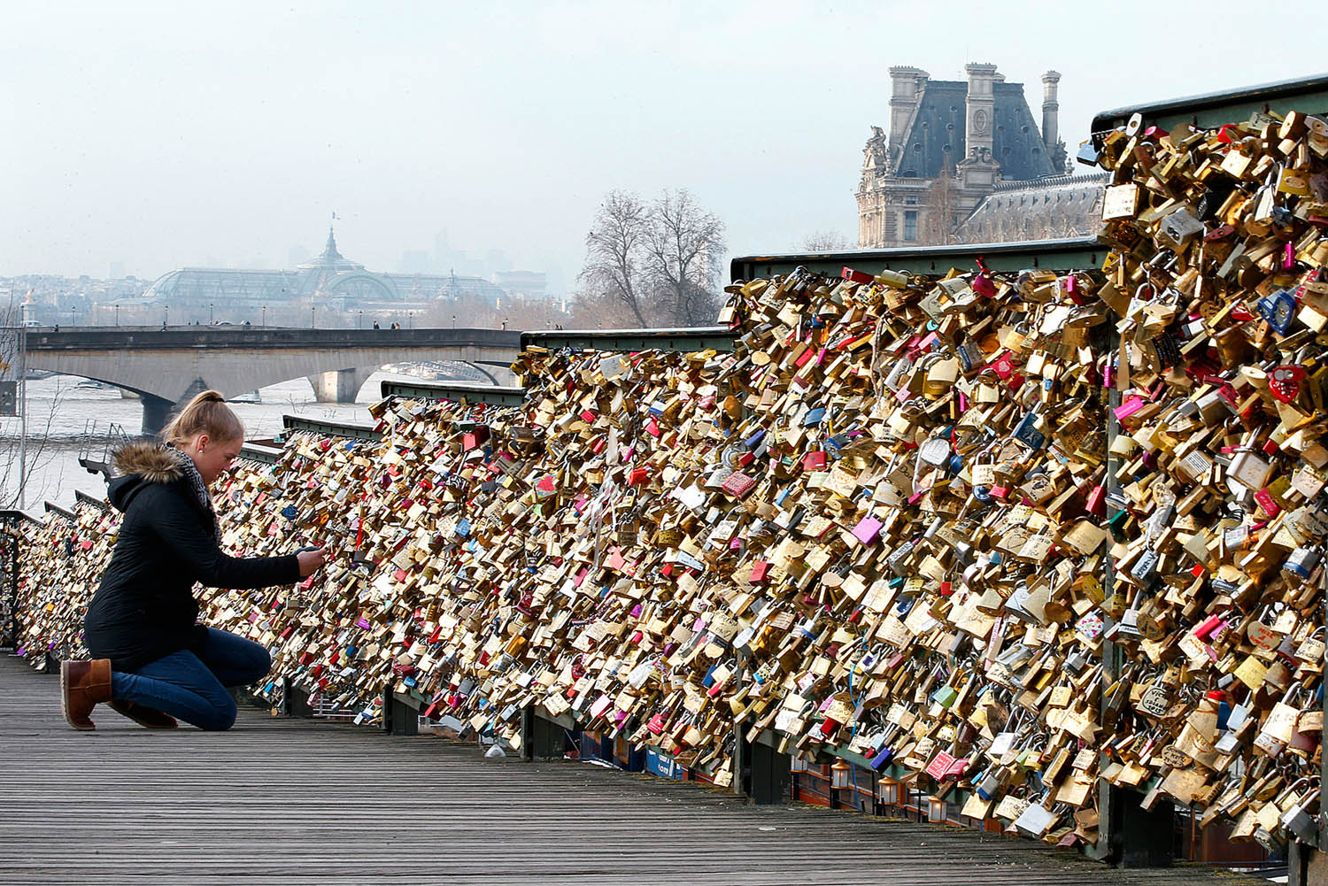 Súlyos szerelem a Szajnán. Egy turista lakatot helyez el a párizsi Pont des Arts-on