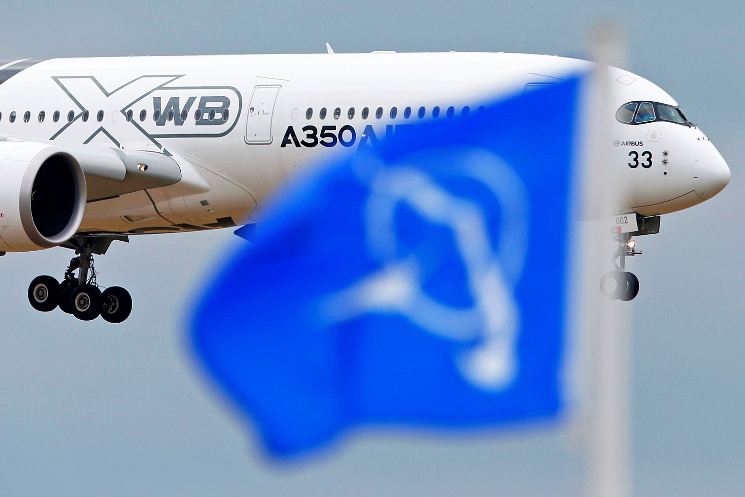 A legújabb Airbus–A350-es óriásgép landol éppen, előtérben a Boeing zászlója