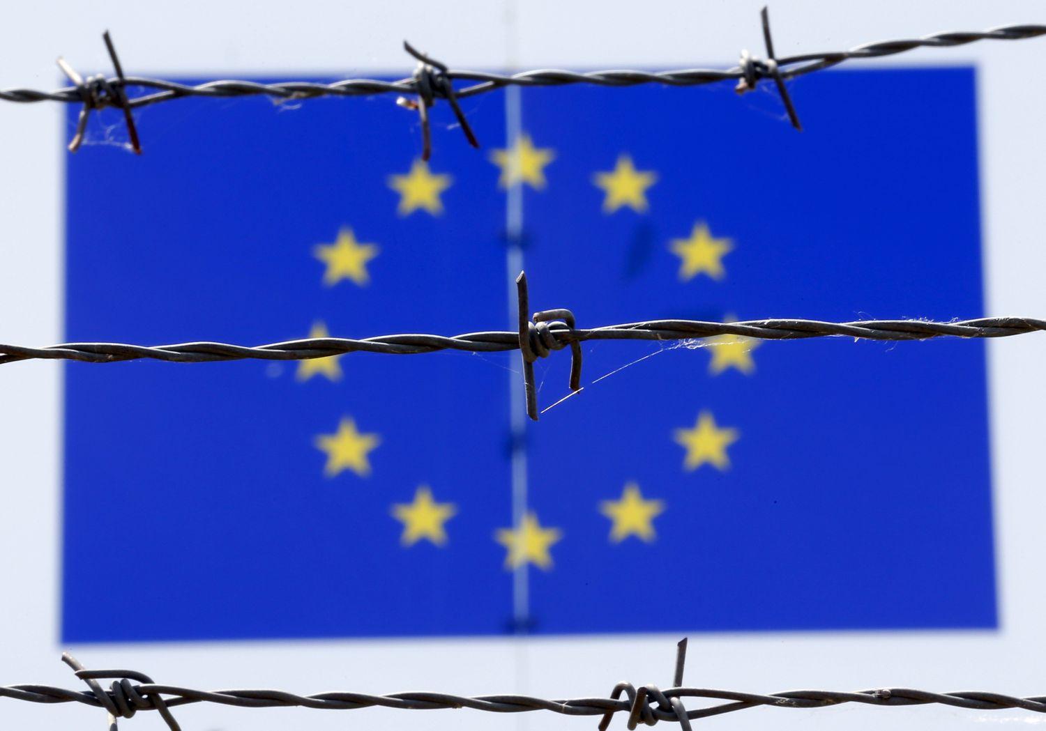 Szögesdrót éktelenkedik az uniós zászló előtt a bicskei menekülttábornál 