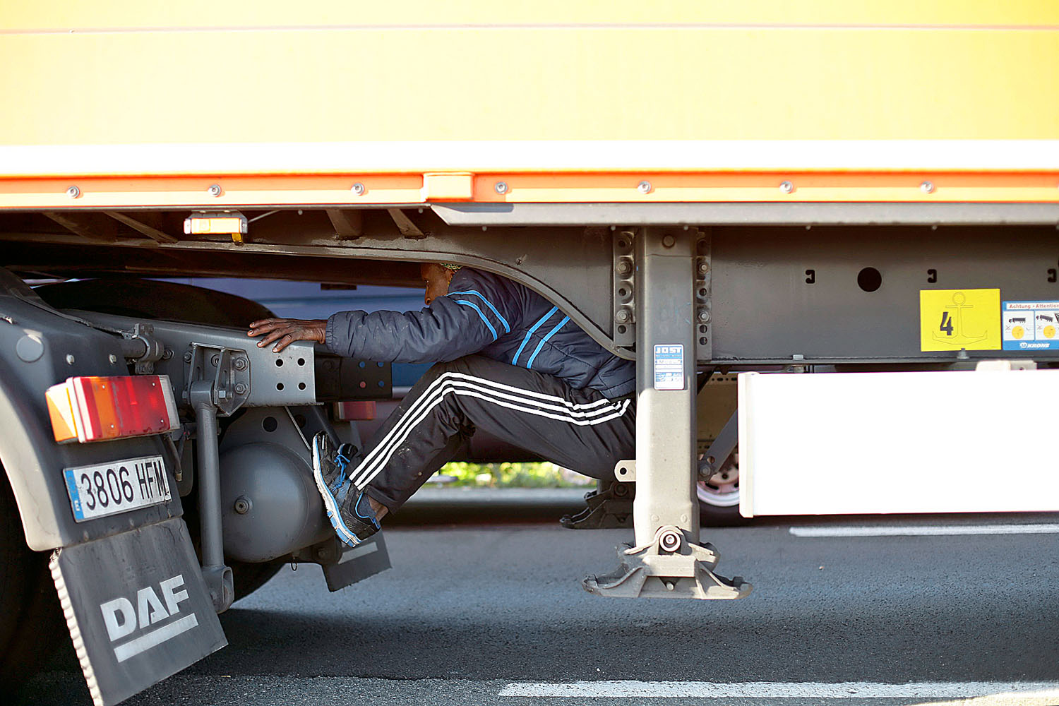 Menekült rejtőzik egy kamion pótkocsija alatt Franciaországban, a Calais kikötőjébe vezető autóúton