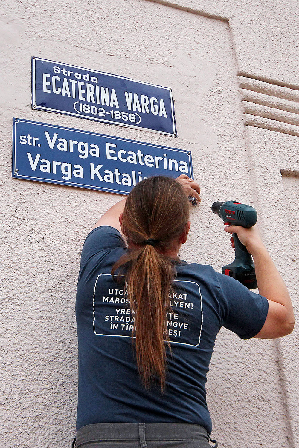 Kétnyelvű utcanévtáblákért küzdő aktivista szerel fel egy magyar táblát Marosvásárhelyen