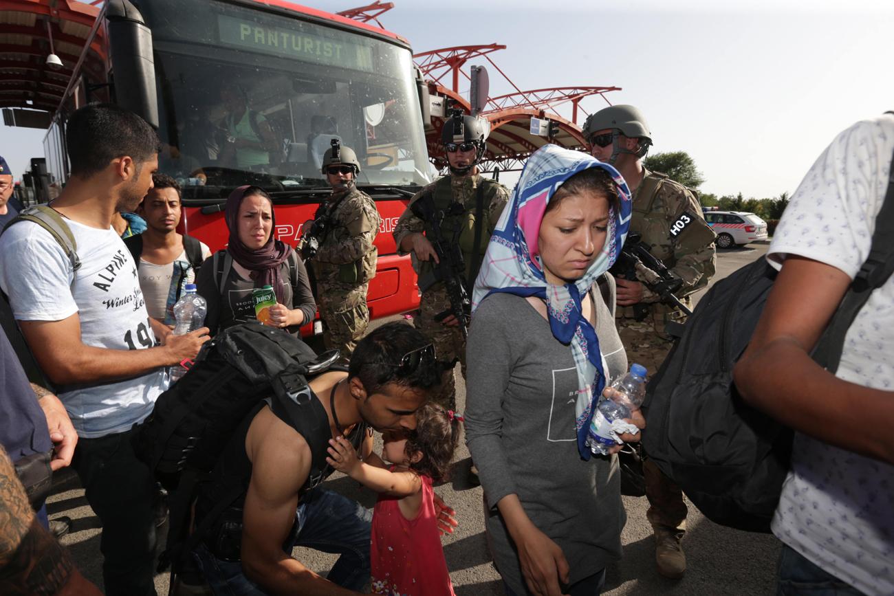 Fegyveresek fogadják a buszokkal érkező menekülteket Beremendnél