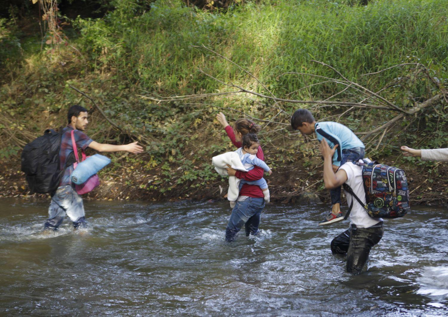 Horvátországból Szlovéniába tartó migránsok kelnek át a Sutla folyón