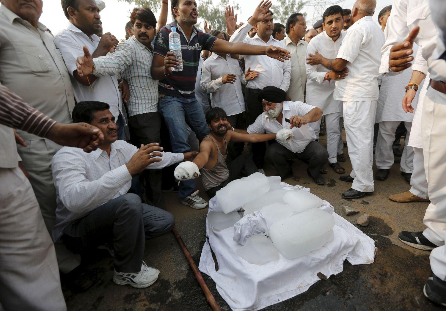 Ülősztrájkkal bénították meg az Agra felé vezető főutat. A képen középen a gyászoló apa (bekötött kezekkel), előtte két csecsemőjének lepedővel letakart holttestei