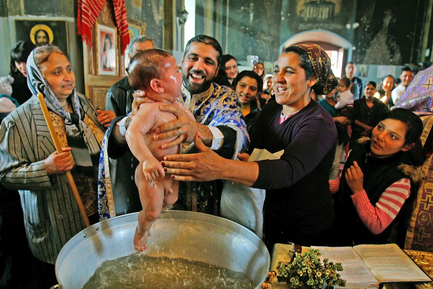 Újszülöttet keresztelnek meg az ortodox rítus szerint a munténiai Sloboziában
