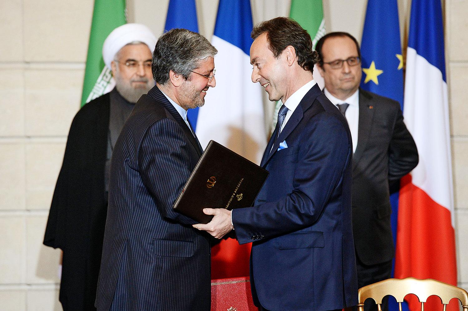 A háttérben Rohani és Hollande, elöl az iráni főtárgyaló Farhad Parvares és az Airbus-vezér Fabrice Bregier 