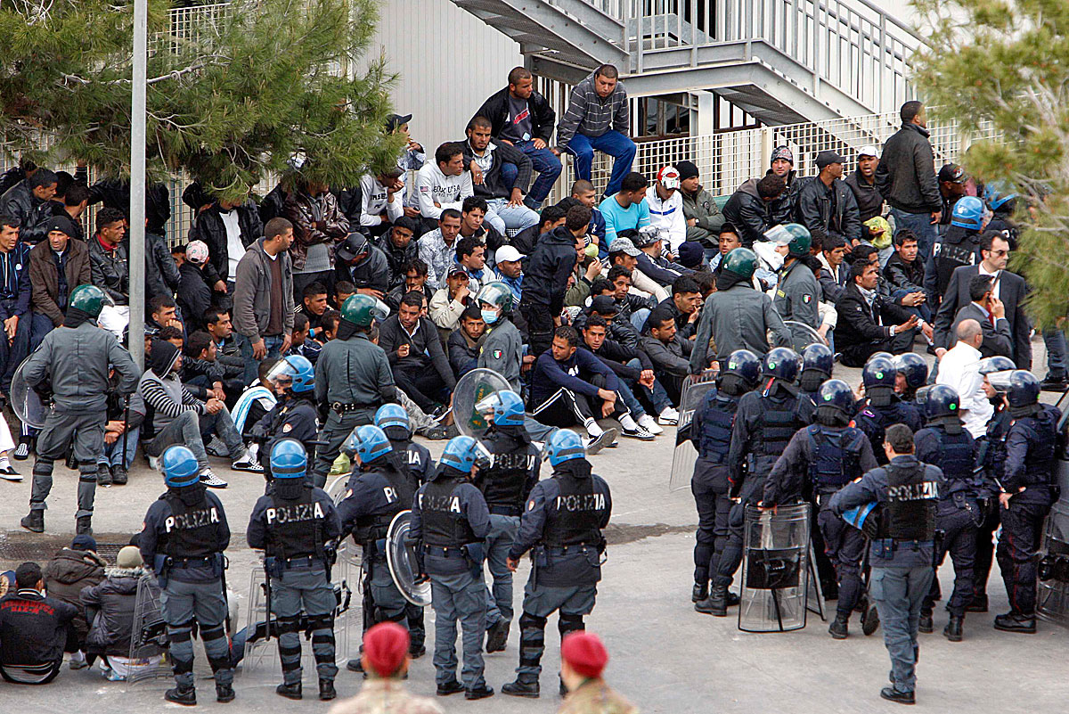 Tunéziai menekültek ülnek a bevándorlási hivatal előtt Lampedusán