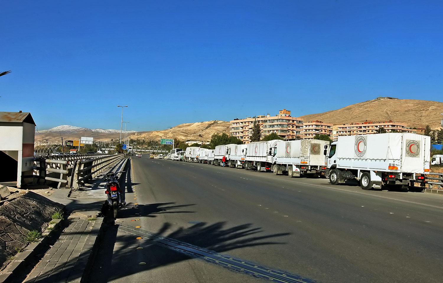 Segélyekkel megrakott teherautók indulásra várnak az ENSZ damaszkuszi képviseleténél