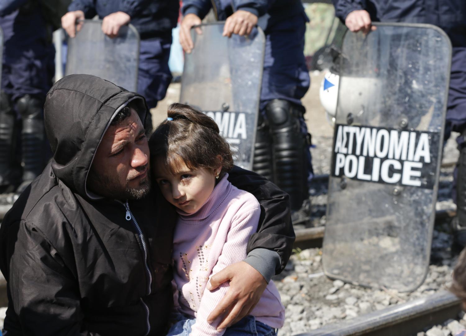 Rendőrkordon előtt ülő menekültek a görög-macedón határnál: vajon ők is csak a 'vonzó megélhetés' miatt jönnének?