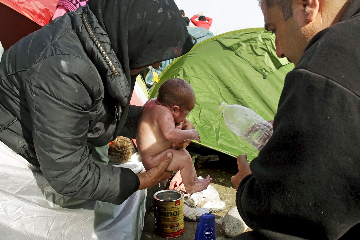 Menekültek fürdetik babájukat a görög–macedón határnál 