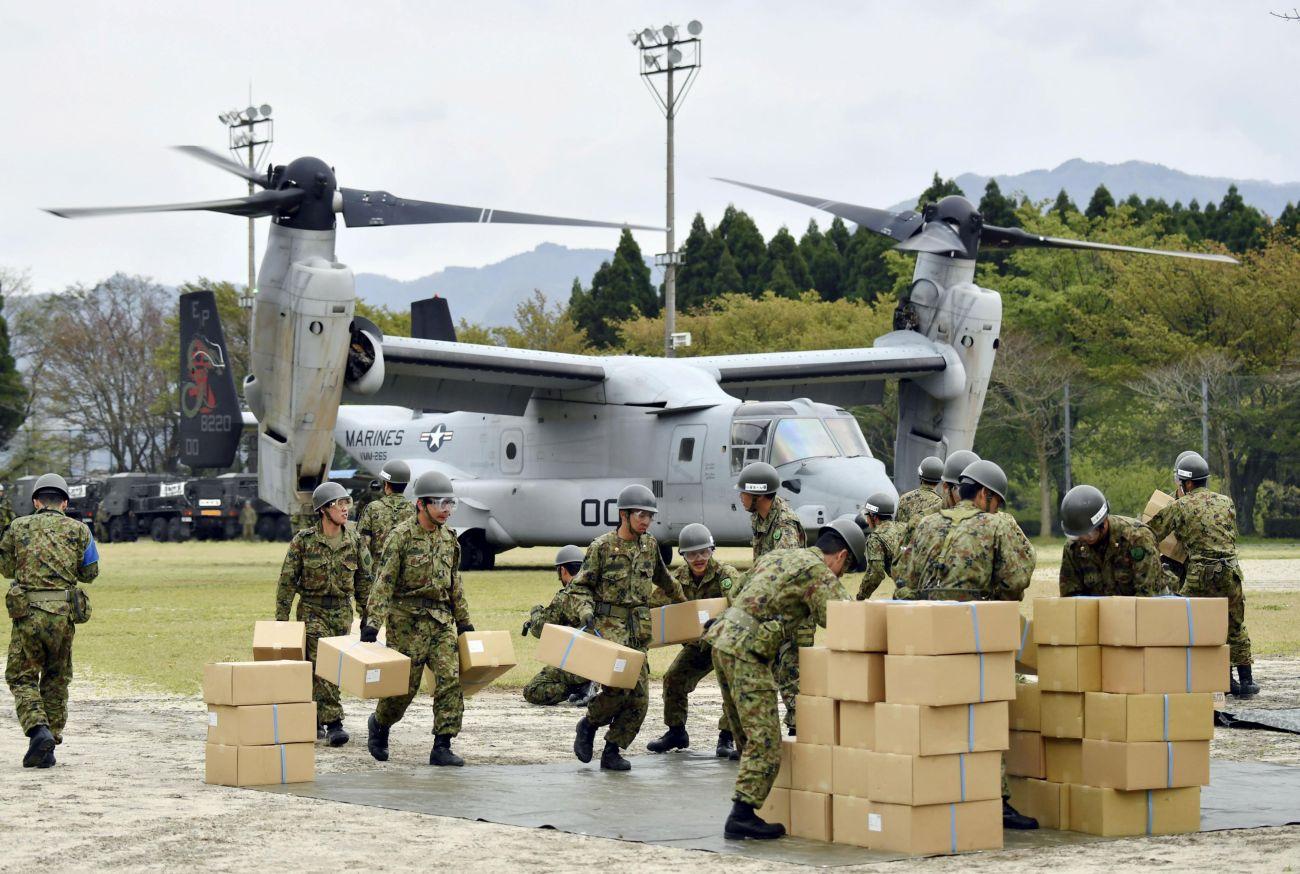 Japán katonák pakolnak ki egy segélyszállítmányt az Egyesült Államok Osprey típusú repülőgépéből.