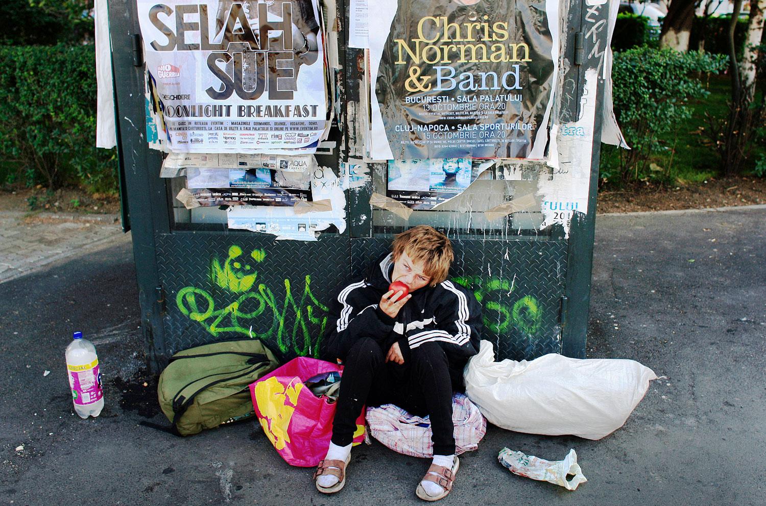 Hajléktalan nő eszik egy bukaresti utcán