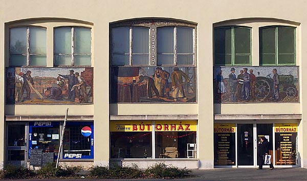 A dunaújvárosi üzletház, Vági Oszkár 1952-ben elkészült épülete, amely átmenet a modern és a szocreál között: ezt jelzik az ablakok alatti színes mozaikok is