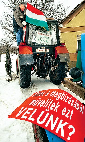 Rubos János lajosmizsei gazdálkodó tiltakozó feliratot és magyar zászlót tesz indulás elõtt traktorára