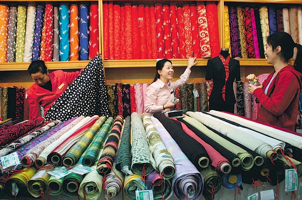 Az eladó egy vásárlóval beszélget Peking egyik textilüzletében