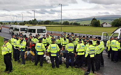 A Gleneaglesbe vezetõ úton ülvõ békés tüntetõket visznek el a rendõrök