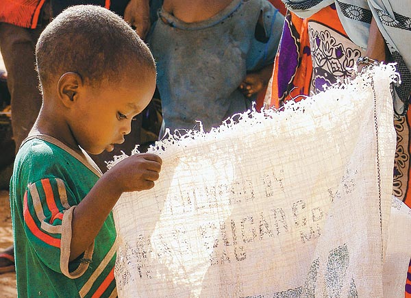 Kenyai kisfiú az ENSZ élelmiszersegély-zsákját vizsgálja. Kenyában hárommillió embert veszélyeztet az éhínség