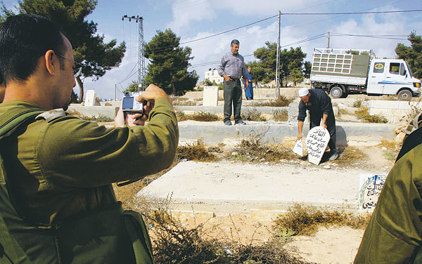Egy, a telepesek által meggyalázott arab temetőt fényképez az izraeli katona Hebronban
