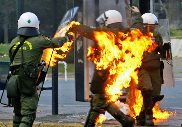 Lángra kapott egy rohamrendőr egyenruhája, amikor tüntetők Molotov-koktéllal eltalálták Athén belvárosában 2008. december 12-én. 