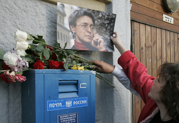 Egy nő koszorút és egy fotót helyez el a néhai Anna Politkovszkaja háza előtt.