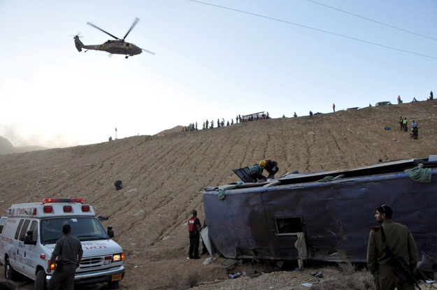 Mentõautó áll egy oldalára fordult busz mellett, miközben az izraeli haderõ helikoptere sebesülteket szállít el a helyszínrõl a dél-izraeli Ejlát üdülõváros közelében