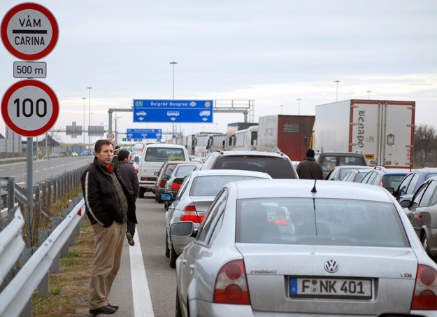 Várakozó autók és utasaik a röszkei határátkelõ közelében