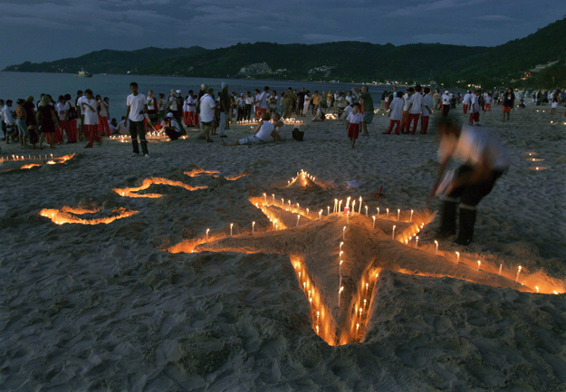 Gyertyákat gyújtanak az áldozatok emlékére turisták és helybeliek a tengerparton, a Phuket szigetén fekvő Patong üdülőhelyen 2008. december 26-án, az Indiai-óceán partvidékén pusztító szökőár negyedik évfordulóján. 