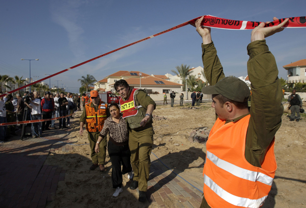 An Israeli soldier helps a woman suffering from shock at the scene of a rocket attack in the southern city of Ashkelon January 5, 2009. Israeli tanks, planes and ground forces pounded Gaza on Monday and the defence minister said the offensive against