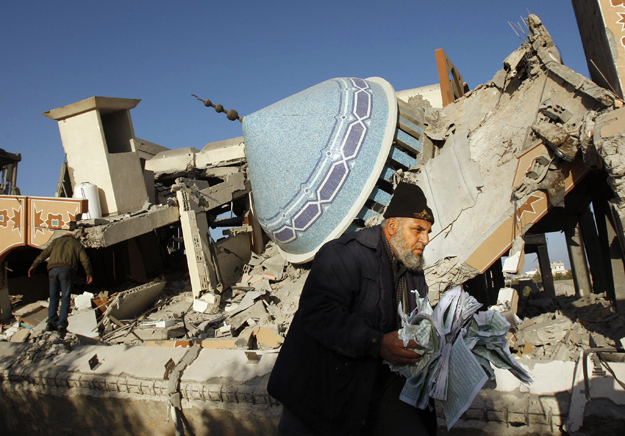 Palesztin férfi a Korán lapjait menti az izraeli légitámadás során lerombolt al-Fadilah mecsetből Rafahban 