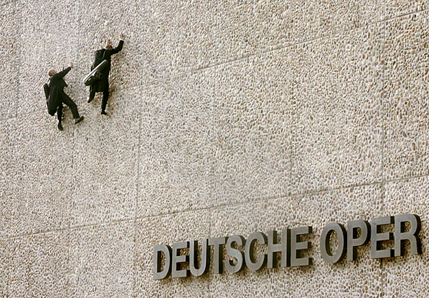 Two unidentified men dressed as musicians climb up the storefront of the Deutsche Oper opera house in Berlin April 23, 2006. 