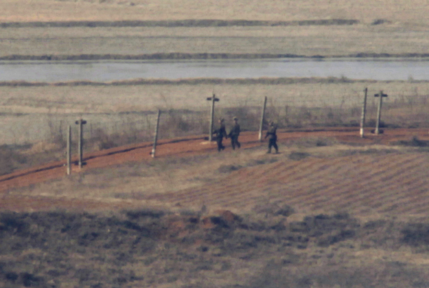 Three North Korean soldiers, carrying rifles, patrol along military fences in the North Korean county of Kaepoong in this picture taken from the South Korean city of Paju, about 45 km (28 miles) north of Seoul, January 30, 2009. North Korea said on F