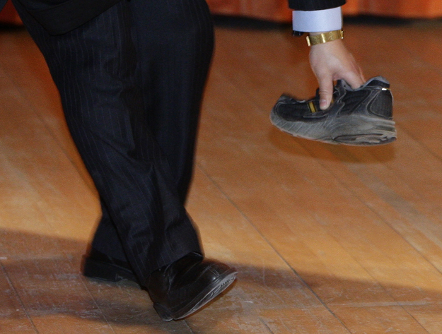 A security guard picks up a shoe that was thrown towards Chinese Premier Wen Jiabao at the University of Cambridge